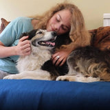 An image of a woman cuddling a dog, sat on a dog incontinence pad.