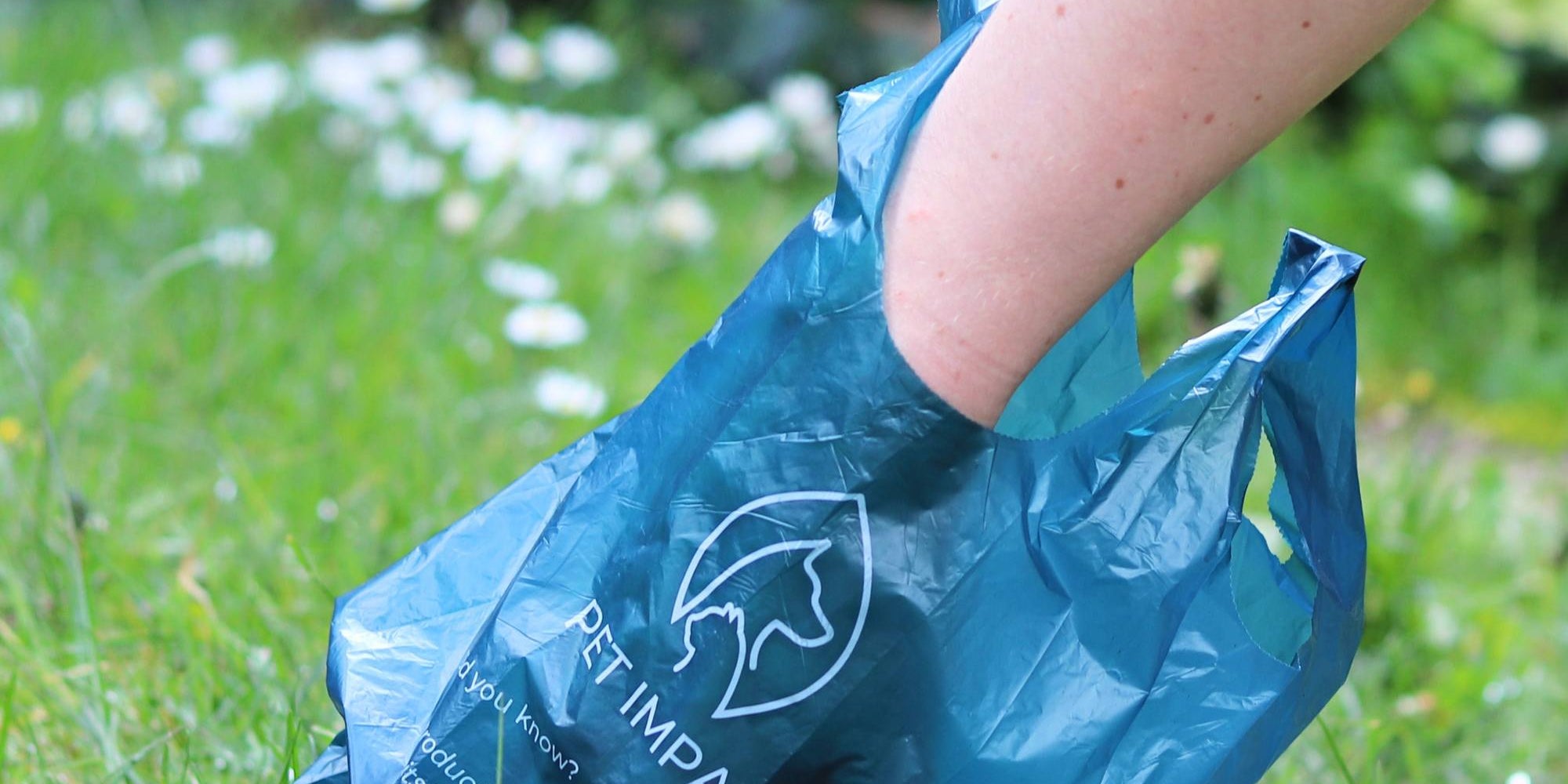 An image of a person using a reseacled poo bag to pick up dog poo